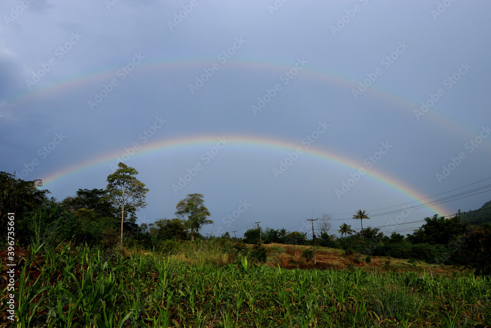Two half-circle rainbows occur in rural farmland. Two half-circle rainbows occur in rural farmland.