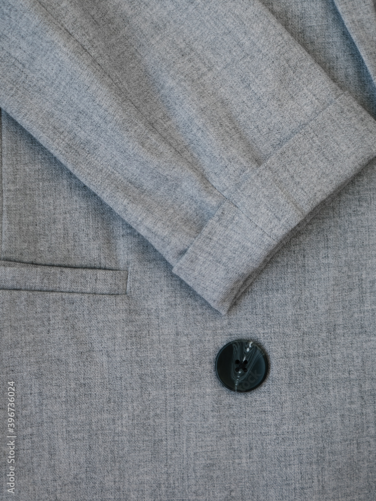 Grey women suit jacket with closeup buttons. Business or formal wear. Gray fabric for tailoring. The grey pinstripe suit cloth. Texture of wool business jacket or coat. Grey women suit jacket with closeup buttons. Business or formal wear. Gray fabric for tailoring. The grey pinstripe suit cloth. Texture of wool business jacket or coat.