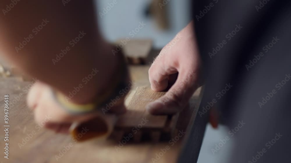 woodworker grinds the grooves on the wood piece with sandpaper for further bonding. carpentry handmade. woodworker grinds the grooves on the wood piece with sandpaper for further bonding. carpentry handmade.