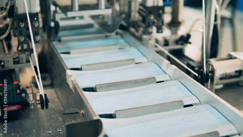 Face masks moving along a conveyor belt at a modern medical mask factory Face masks moving along a conveyor belt at a modern medical mask factory