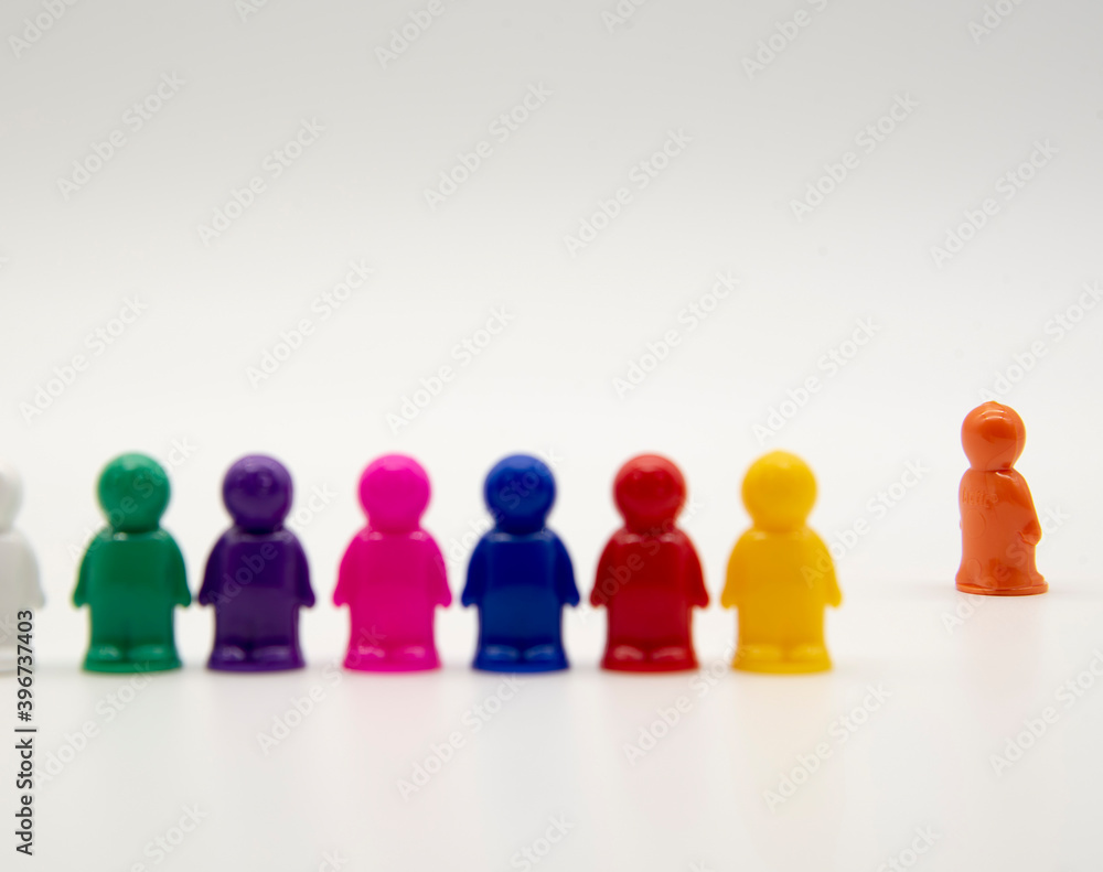 Board game colorful plastic figures stand on a white background, one man in the distance. Board game colorful plastic figures stand on a white background, one man in the distance.