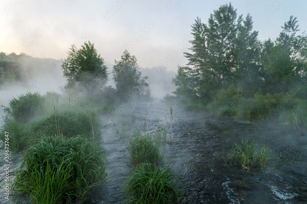 Rough river with fast-flowing in the fog and mist on the background