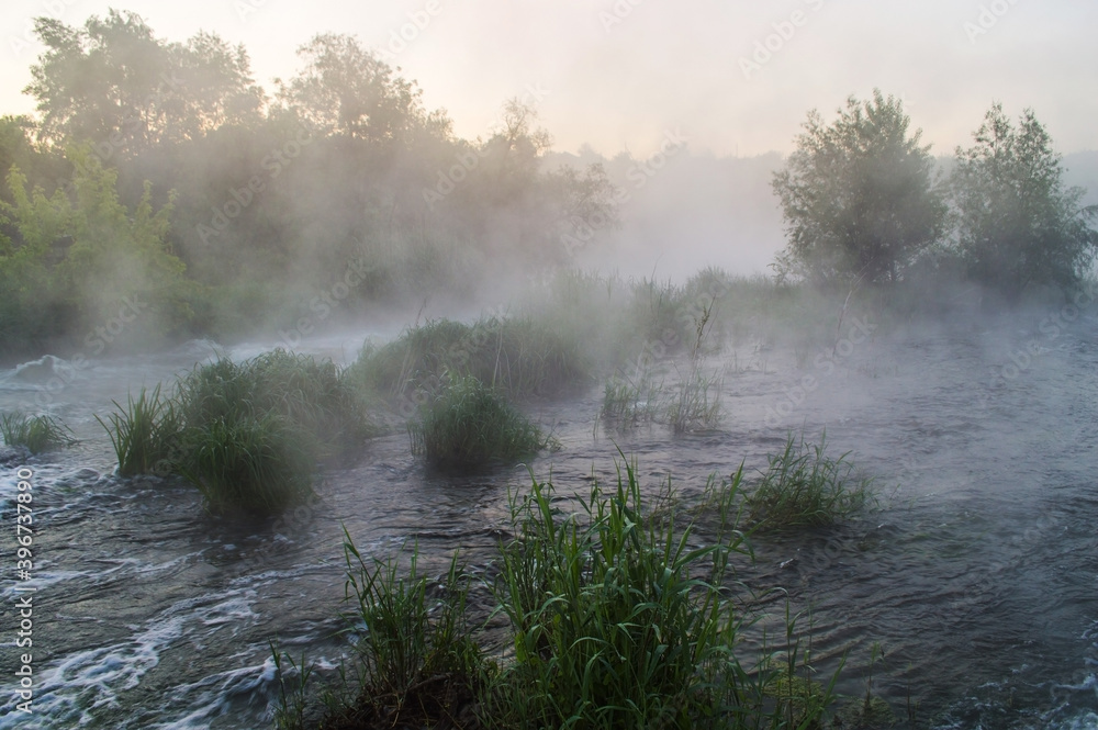Rough river with fast-flowing in the fog and mist on the background