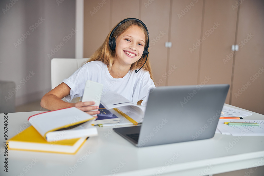 Content schoolgirl with a mobile phone opposite to a laptop Content schoolgirl with a mobile phone opposite to a laptop