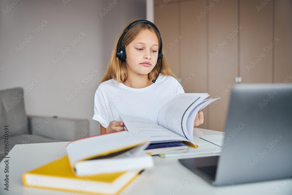 Sad teenager in a headset seeking a desired page Sad teenager in a headset seeking a desired page