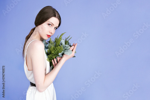 Girl with a bouquet isolated on a purple background. Girl with red lips holds a bouquet of flowers.