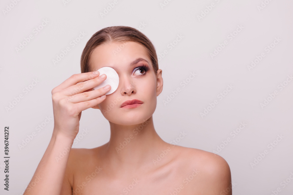 Beautiful girl removes makeup. Cleansing the skin from evening make-up. Cotton pads and tonic. Cosmetics remover. Isolate background copy-space for text. Close-up portrait. Purity face. hygiene Beautiful girl removes makeup. Cleansing the skin from evening make-up. Cotton pads and tonic. Cosmetics remover. Isolate background copy-space for text. Close-up portrait. Purity face. hygiene