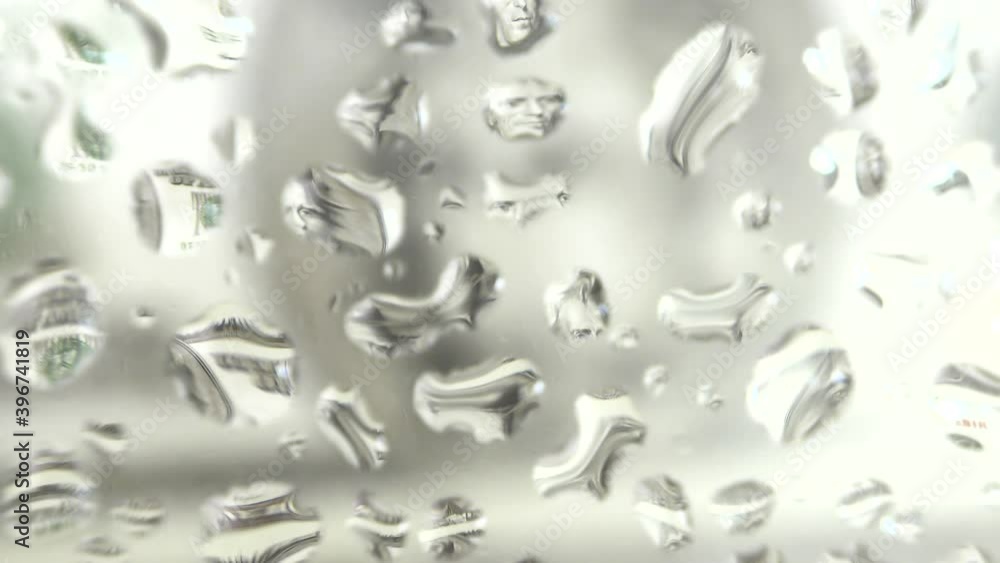 Video image of dollar paper bills in drops of water on a blurred background of banknotes. Video image of dollar paper bills in drops of water on a blurred background of banknotes.