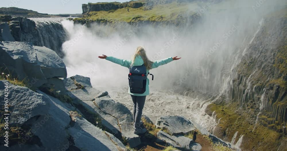 Woman standing on the edge of the cliff and raising her hands up in the ...