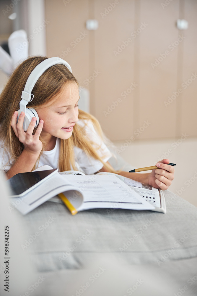 Underage student enjoying the tunes during a work with dictionary Underage student enjoying the tunes during a work with dictionary
