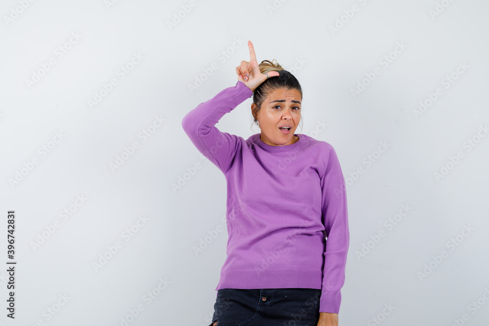 lady showing loser sign over head in wool blouse and looking ...