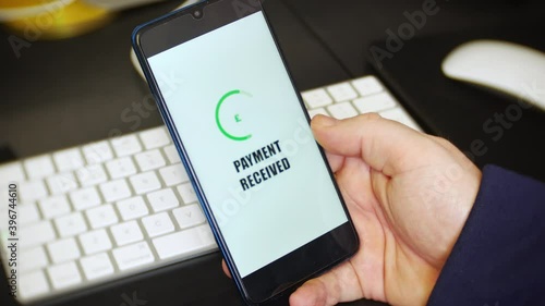 A payment received notification is received on a payment app on a cell phone. The mobile application displays an English pound sign to represent money being received. photo