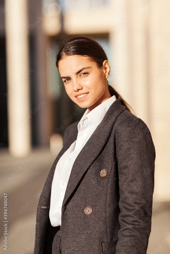 © Comeback Images - Waist up portrait of confident and beautiful brunette woman in white shirt and grey coat looking at camera and smiling standing in street © Comeback Images - Waist up portrait of confident and beautiful brunette woman in white shirt and grey coat looking at camera and smiling standing in street
