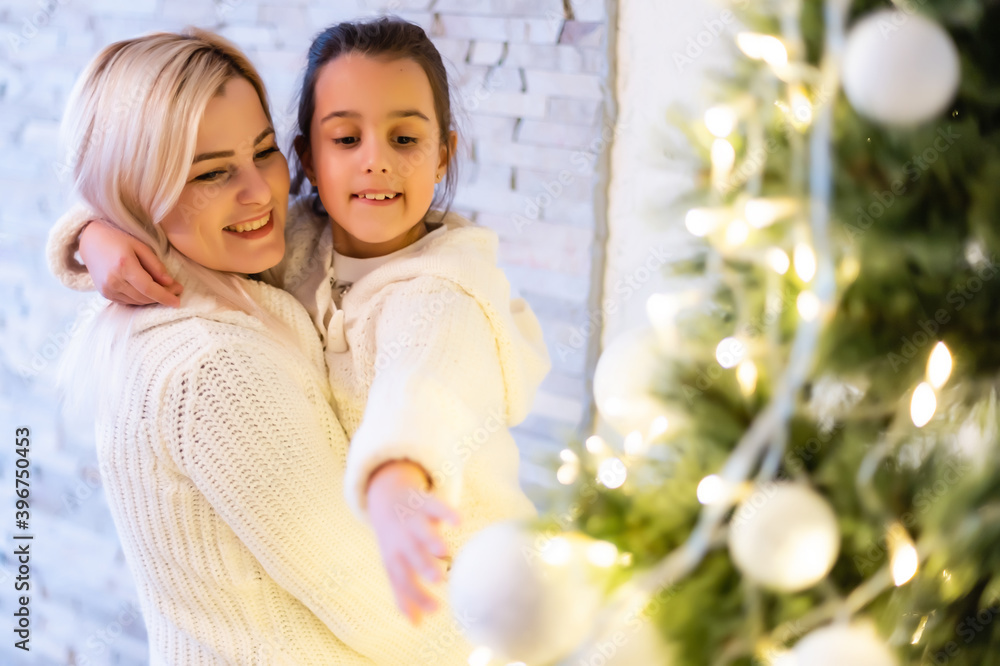 Obraz premium Daughter with her mother near the Christmas tree.