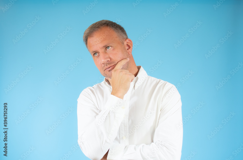 Young man in casual shirt thinking over blue background.