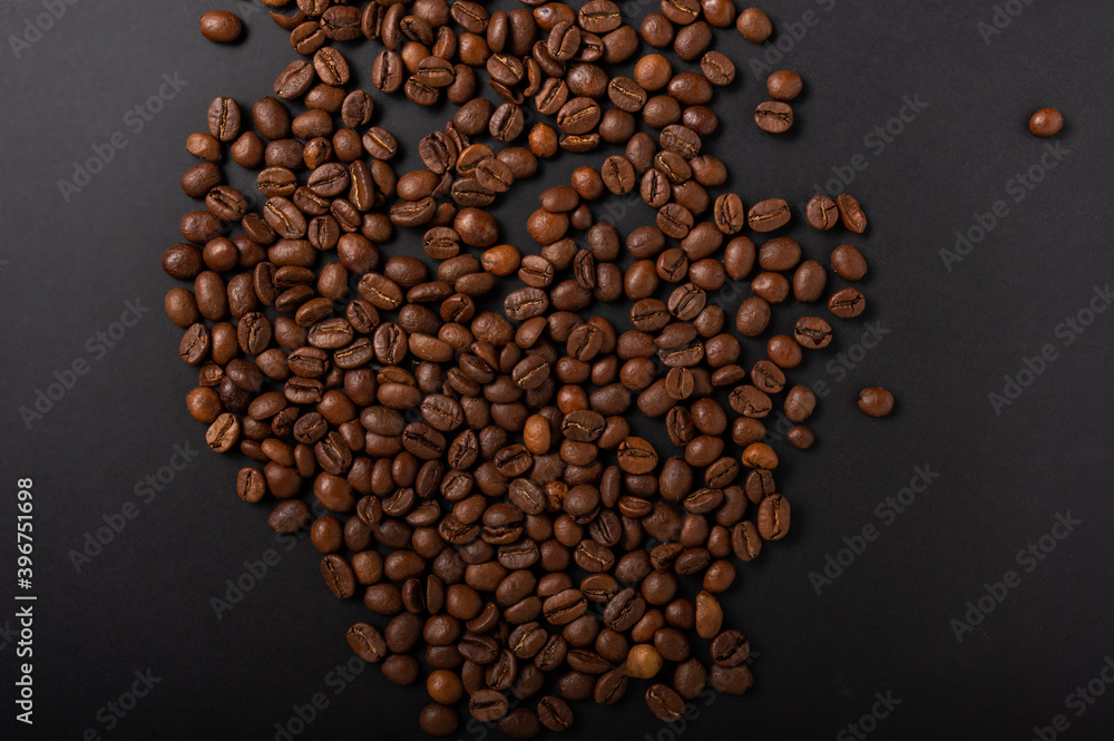 Sprinkled coffee beans in the center of the table. Grains on a black background.