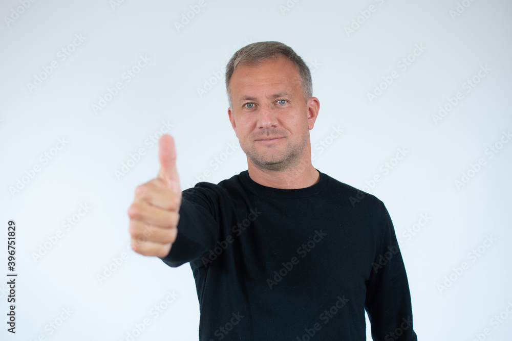 Happy man wearing casual black sweater with thumb up sign on white background Happy man wearing casual black sweater with thumb up sign on white background