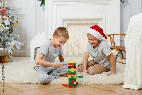 two eight-year-old boys are playing in the New Year's interior. build a pyramid of blocks. christmas concept