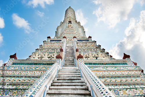 White temple Wat Arun prang with stairs and sculptures on blue sky background. Architectural landmark in Bangkok, Thailand photo