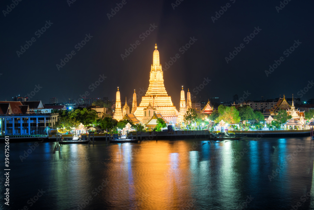 Night illuminated Temple of Dawn or Wat Arun and its reflection in Chao Phraya River after sunset. Bangkok, Thailand
