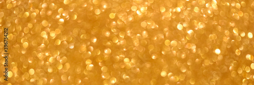 An abstract gold background with sparkle lights and bokeh. Christmas background or greeting card. Banner.