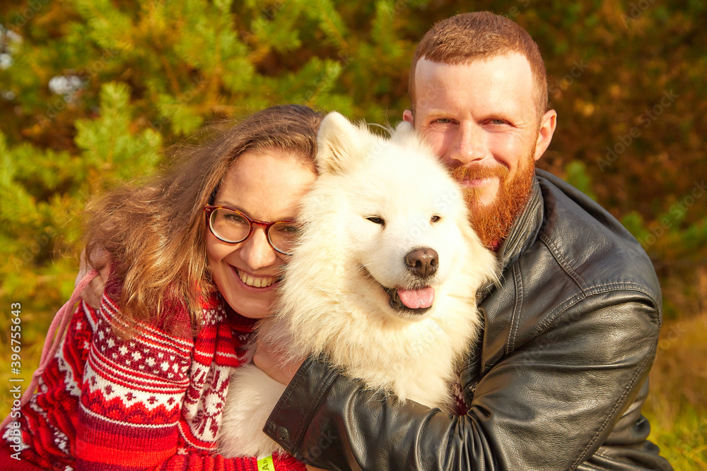 Cute girl and man with dog in the autumn sunny day. Friendship of man, woman and dog. Couple walking with pet. Cute girl and man with dog in the autumn sunny day. Friendship of man, woman and dog. Couple walking with pet.
