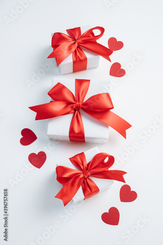 Gift boxes with red ribbon and hearts on white background. Valentines day background. Top view  flat lay. Vertical.