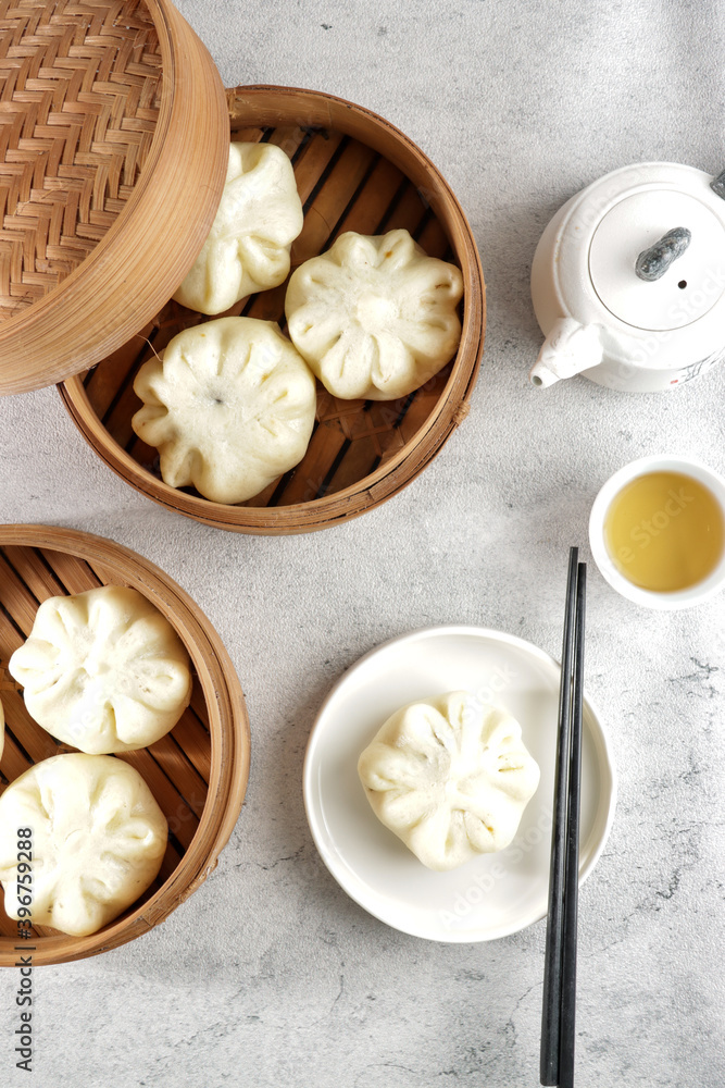 Bakpao or pao or chinese steamed bun in traditional bamboo steamer serve with tea in top view.