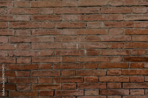 Rustic brick wall with colorful red brown bricks uneven and cracked with space for texture background