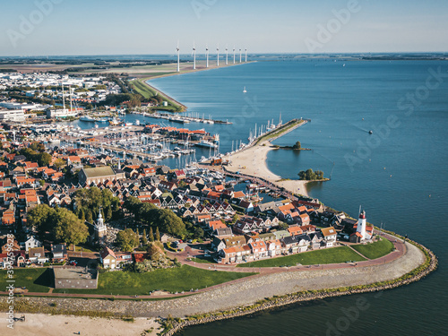 Historic fishing town of Urk in Flevoland, The Netherlands, featuring a lighthouse and a harbor, with wind turbine farm on the background. Popular tourist destination. Aerial view.  photo