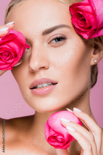 beautiful blonde woman with rose flowers isolated on pink