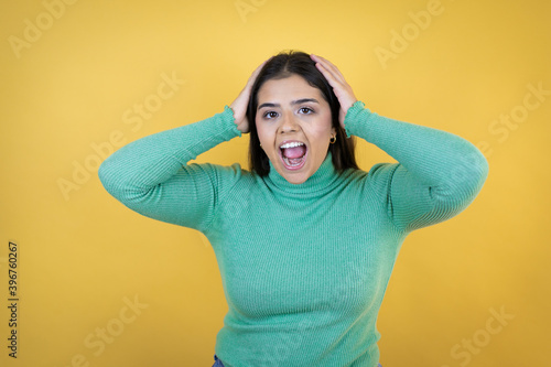 Young caucasian woman over isolated yellow background crazy and scared with hands on head, afraid and surprised of shock © Irene