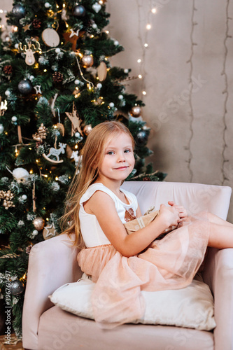 Beautiful little girl with gift near Christmas tree at home © Elena Kratovich