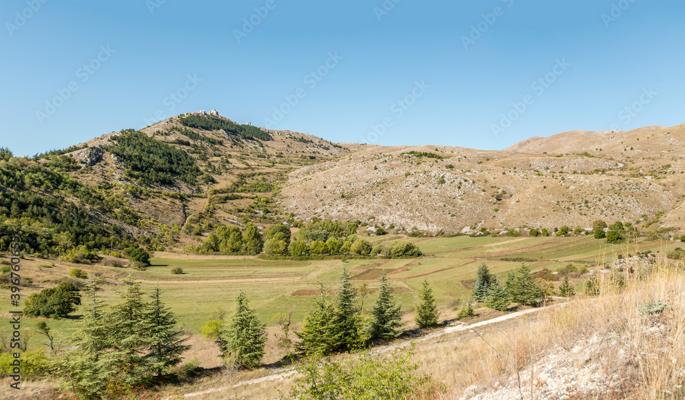 Naklejka premium green upland below medieval castle ruins, Rocca Calascio , Abruzzo, Italy