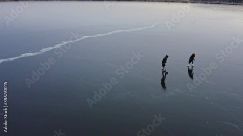 Couple skating on a frozen lake in a strong wind.