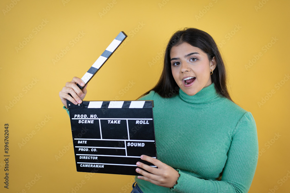 Young caucasian woman over isolated yellow background holding clapperboard very happy having fun Young caucasian woman over isolated yellow background holding clapperboard very happy having fun