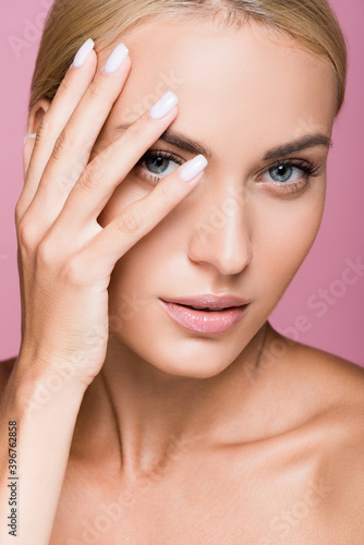 beautiful blonde woman posing with hand on face isolated on pink