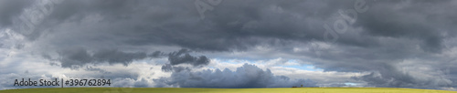 Storm clouds over the fields. Landscape at sunset. Tragic gloomy sky. Panorama. The sun is hidden.