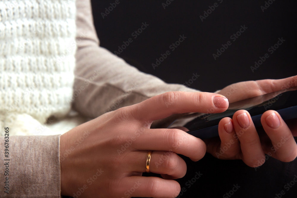 Hands holding mobile phone close up. Young woman in knitted white sweater messaging with smartphone. Female browsing site on cellphone Hands holding mobile phone close up. Young woman in knitted white sweater messaging with smartphone. Female browsing site on cellphone