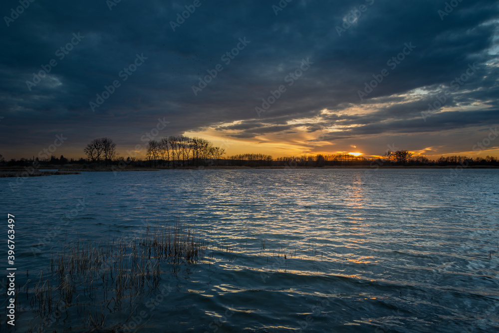 Sunset and dark clouds over the lake with reeds