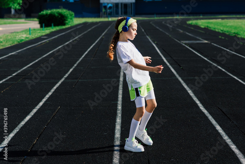 Girl jogging on a sunny summer evening, laying on treadmill, stadium, physical training, back to school.