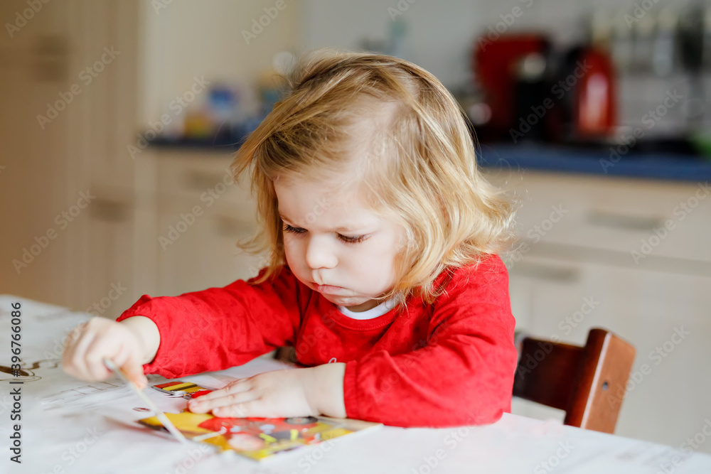 Adorable little toddler girl blonde child, playing with puzzles at home or kindergarten. Cute happy healthy child puzzling and making picture. Development and education step for baby Adorable little toddler girl blonde child, playing with puzzles at home or kindergarten. Cute happy healthy child puzzling and making picture. Development and education step for baby