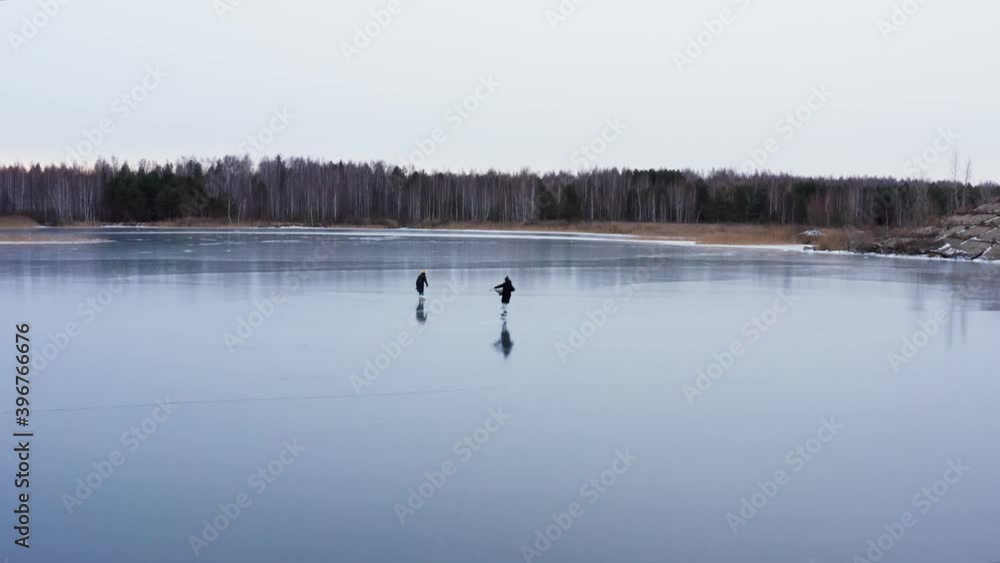 People go ice skating near the banks of a frozen river. People go ice skating near the banks of a frozen river.