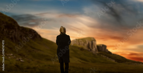 Silhouette of a woman walking in nature green mountain valley.