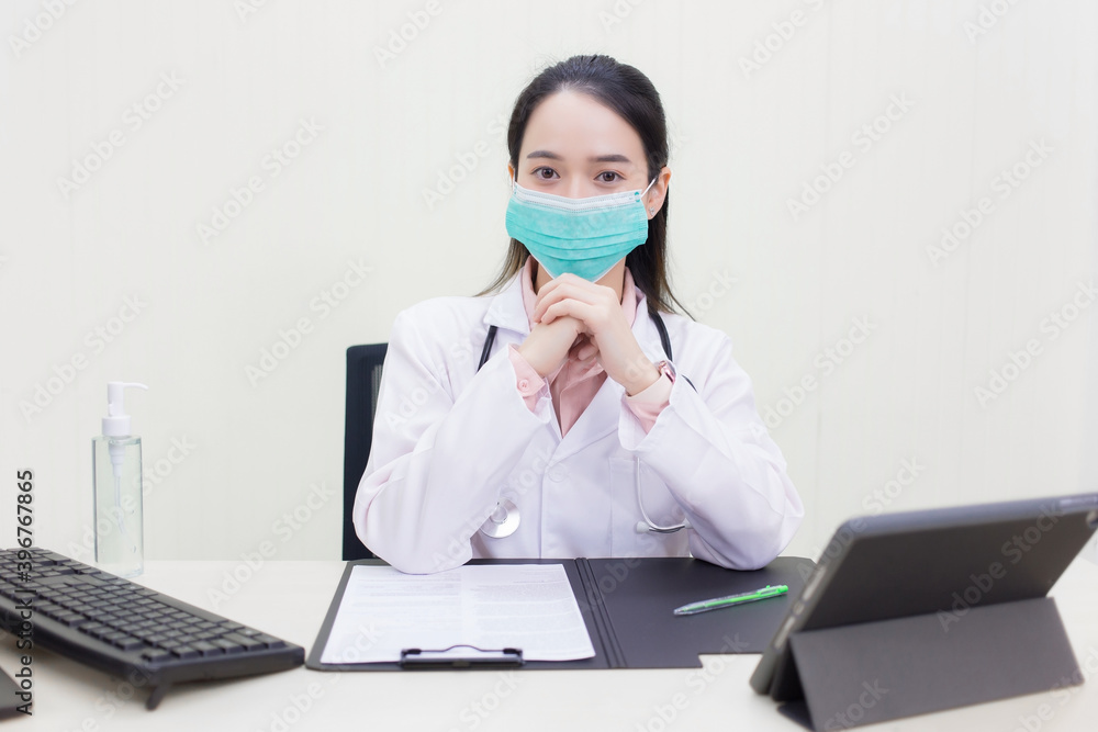 Coronavirus protection concept. Asian female doctor Sitting in the examination room wearing a mask and pondering. Coronavirus protection concept. Asian female doctor Sitting in the examination room wearing a mask and pondering.
