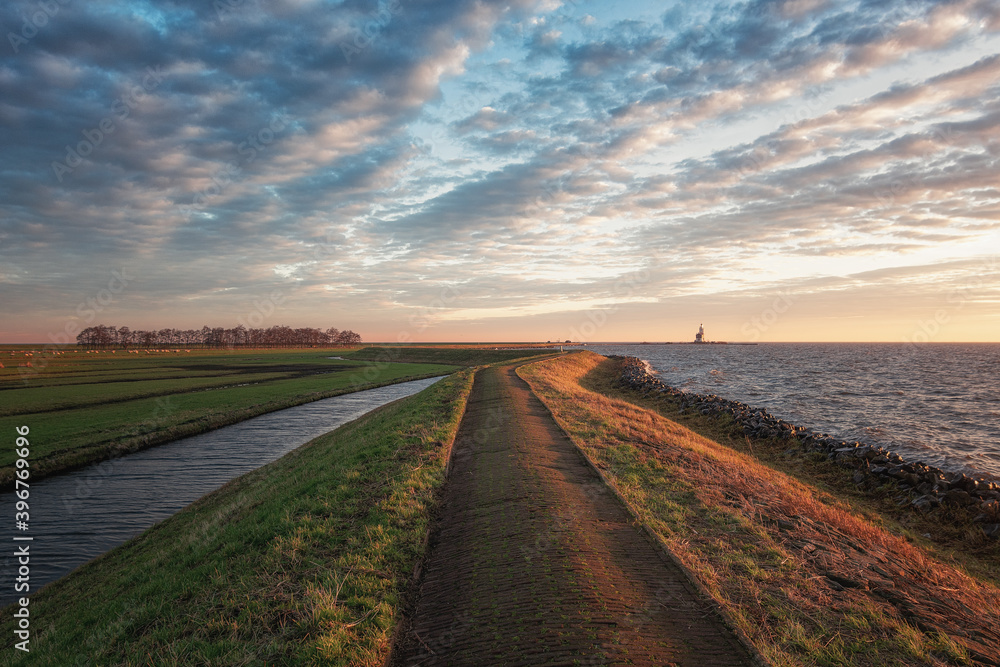 Φωτογραφία The dike around the island of Marken during sunrise with the lighthouse Het Paar