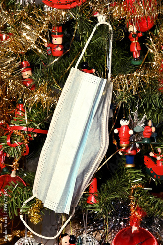 Christmas tree with Coronavirus face mask hanging from the tree, decorated with Covid-19 safety mask and Christmas decorations