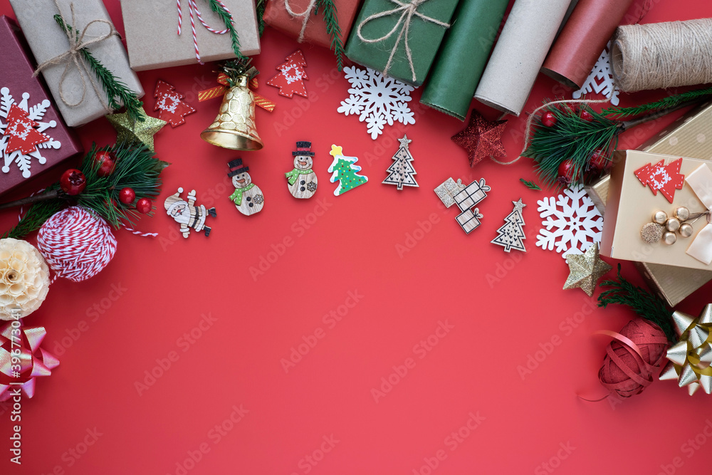 Obraz premium Top view above of Christmas holiday background. Composition with fir pine branches, ribbon, bow and gift box decorations on red background. Winter, Christmas, new year concept. Flat lay, copy space.