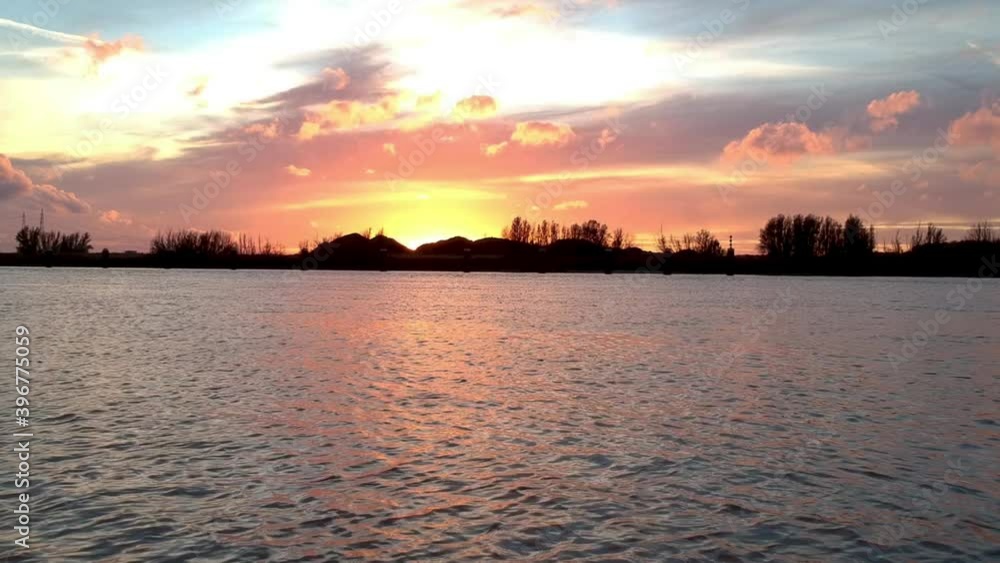 Pushing towards the sunset with a horizon filled with vibrant colors contrasting a silhouetted riverside. Pushing towards the sunset with a horizon filled with vibrant colors contrasting a silhouetted riverside.