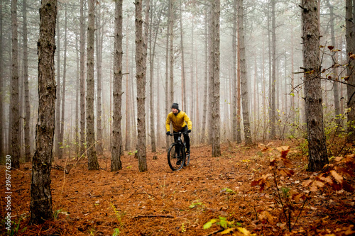 Young man biking through autumn forest